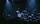 A small club stage lit in blue, with the crowd gathered in front of it.