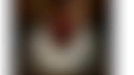 portrait of a coffee mug with a broken, missing handle. sitting on a fireplace.