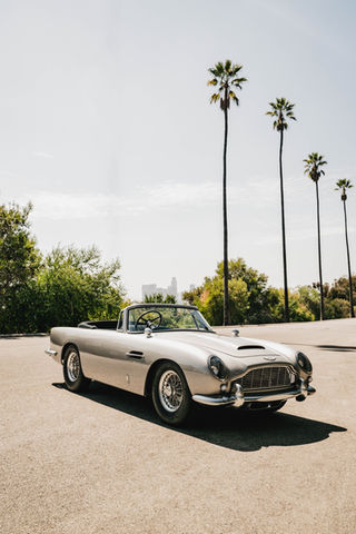 Silver Aston Martin DB5J parked under palm trees during a lifestyle photoshoot for Rennauto Brisbane.