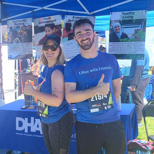 Two Denver Colfax Marathon runners, posing with thumbs up in front of an information stand.