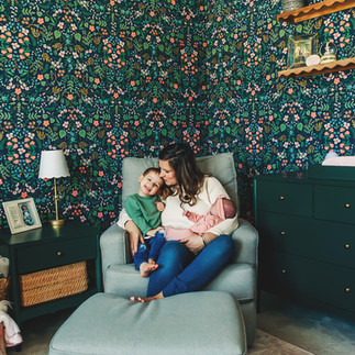 mom sitting in nursery with toddler and newborn