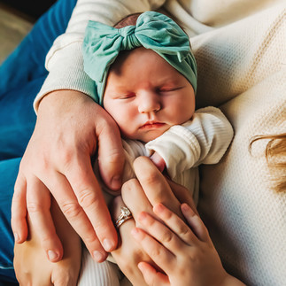 newborn baby with hands laying on top while holding her