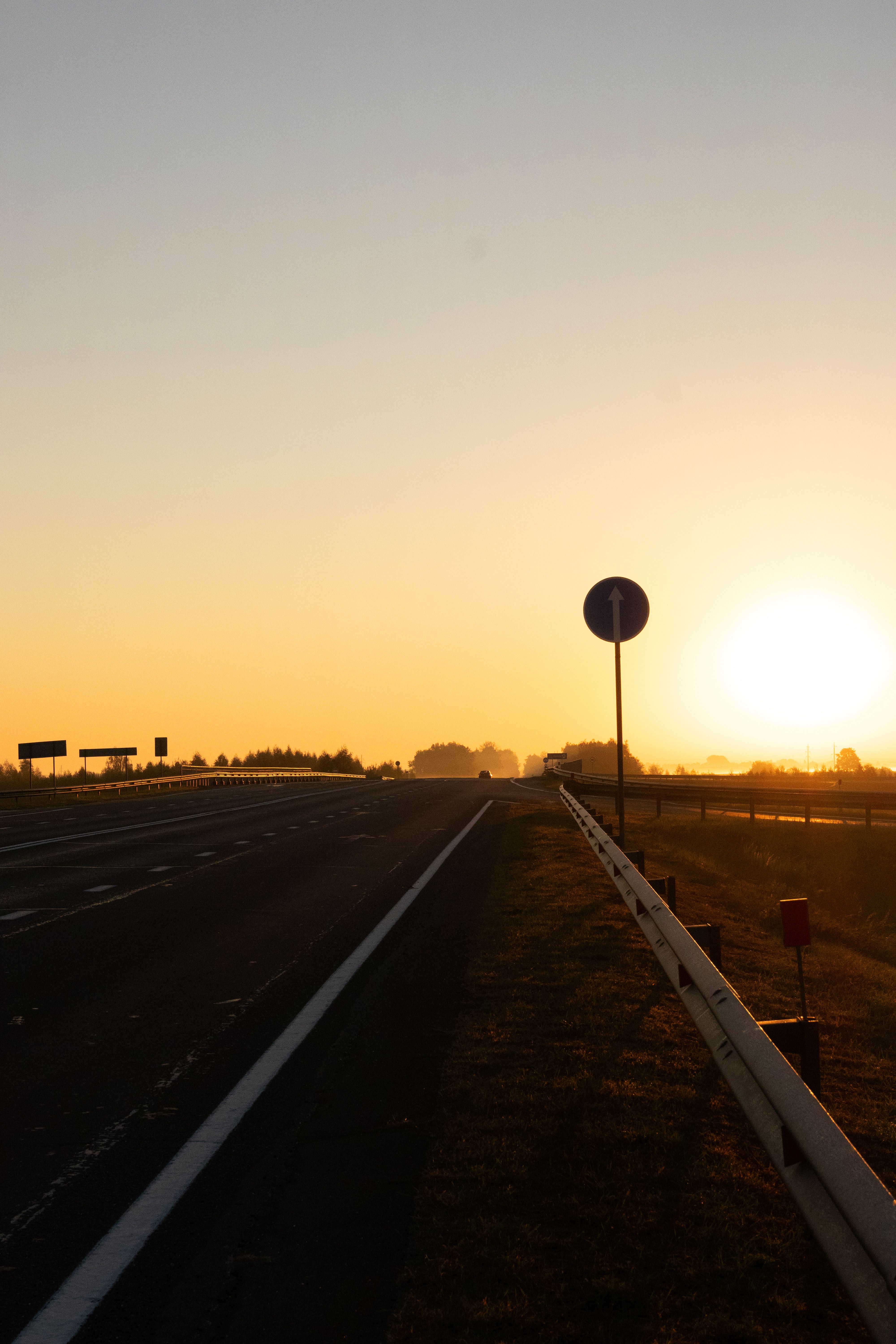 Peaceful sunrise over an empty highway with road signs silhouetted in the distance