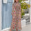 Thumbnail: Model wearing high neck, long-sleeve, long dress with pink and blue timeless elegance pattern