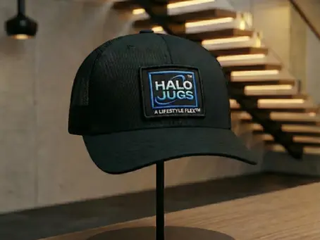 Black Halo JuGs™ trucker hat featuring the official A Lifestyle Flex™ trademark patch, displayed in a modern luxury home setting.
