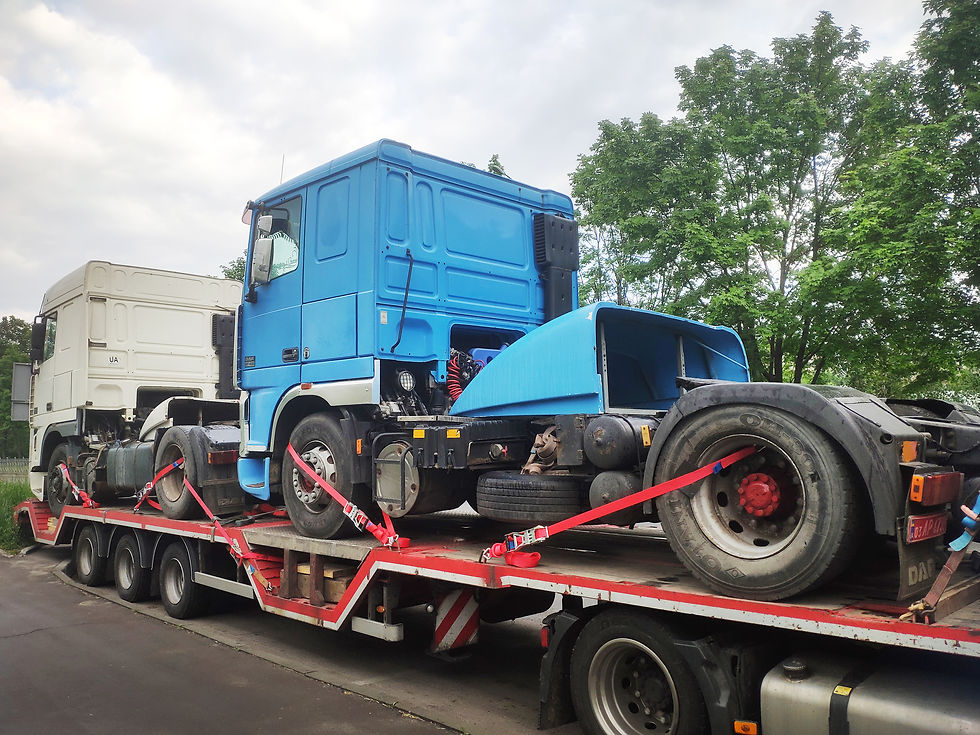 blue-truck-is-securely-transported-trailer-using-red-straps-another-white-truck-appears-ba