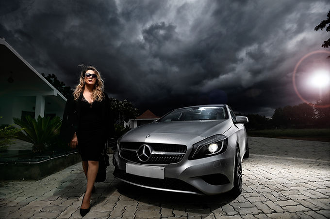 Title: Luxury Lifestyle Photography – Mercedes-Benz Automotive Shoot by Rakesh Vishwanath Photography Hyderabad. Alt text: Woman in black dress and sunglasses standing beside silver Mercedes-Benz under dramatic stormy sky, luxury lifestyle photoshoot by Rakesh Vishwanath Photography Hyderabad. Meta description: Luxury automotive lifestyle photography featuring a silver Mercedes-Benz and model in black under a dramatic stormy sky, captured by Rakesh Vishwanath Photography, Hyderabad. Specialists in luxury lifestyle and automotive photography.
