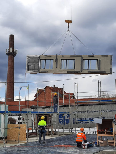 Vorgefertigtes Modul wird während der Montage auf der Baustelle von einem Kran gehoben.
