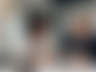 モダンなオフィスで、2人のビジネスパーソン(若い黒人女性と中年白人男性)がタブレットを囲んで熱心に営業戦略について話し合っている。B2Bセールスの個別進捗ミーティングをイメージさせる、協力的で前向きな雰囲気の横長の画像。