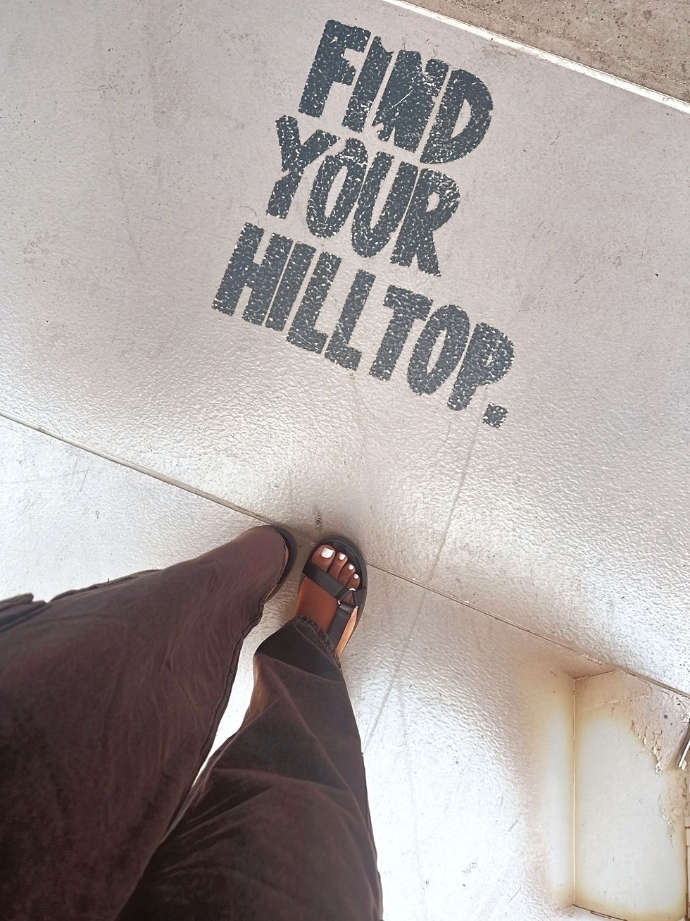 Woman stepping forward on sidewalk with the words Find Your Hilltop beneath her feet.