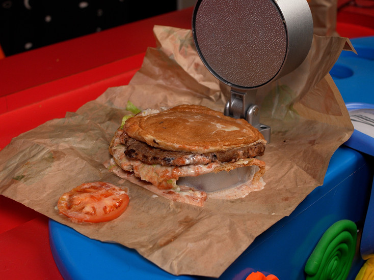 After the Whopper has been smashed, a tomato fell out and is oozing sauce. It is not as flat as the McDonald's cheeseburger.