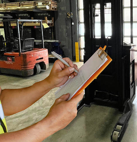 man holding a clipboard inspecting a lift truck for safety