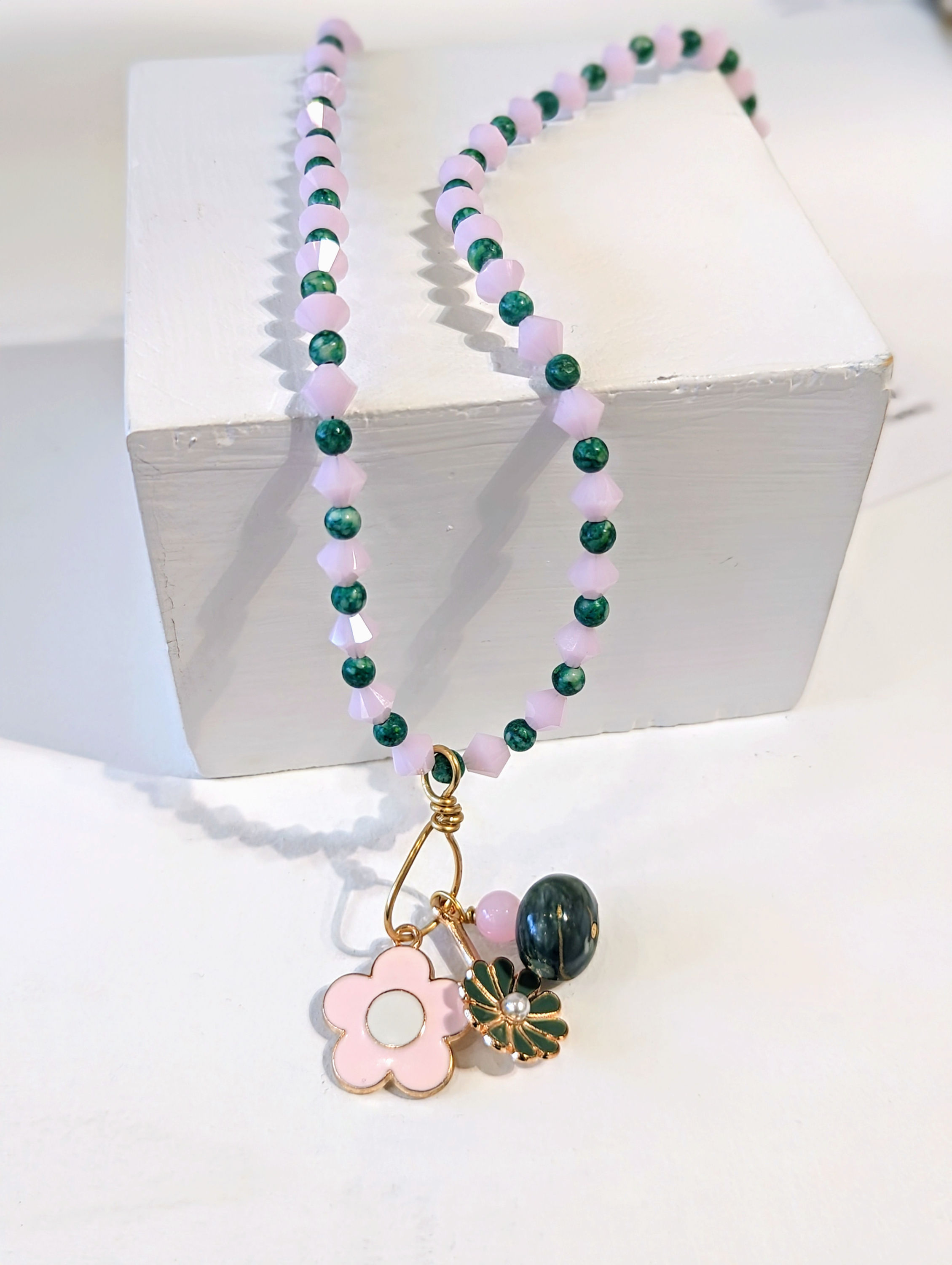Beaded necklace with pink flower and green leaf charms