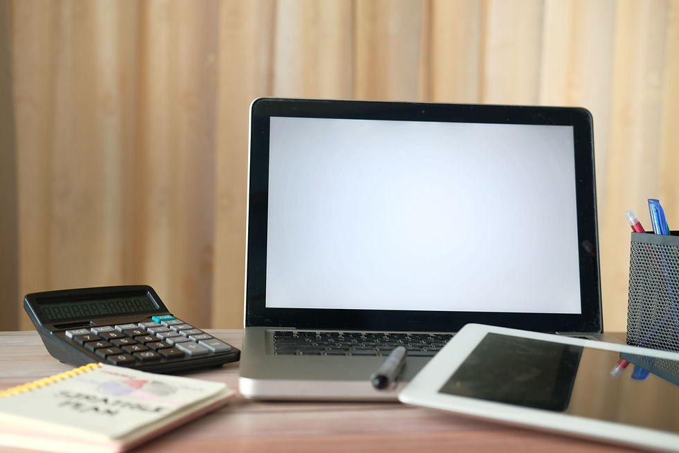Laptop, tablet, and calculator on a desk for comparing Copilot vs ChatGPT for business