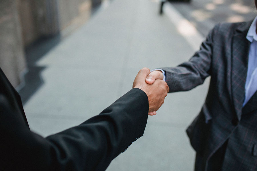 Two people shaking hands over a vendor contract