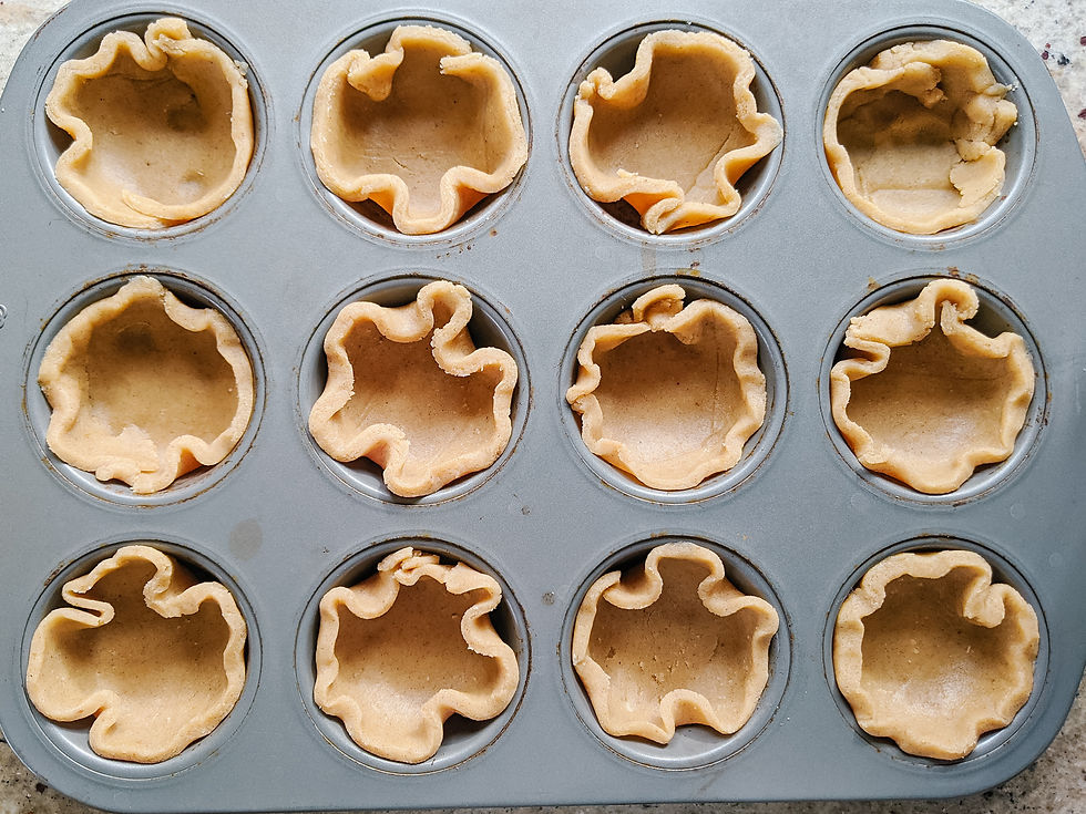 a 4 muffin by 3 muffin baking pan is shown filled with un-baked, hand-formed tart shells that were cut from our Paleo pastry dough. The shells are a golden brown even before they're baked!
