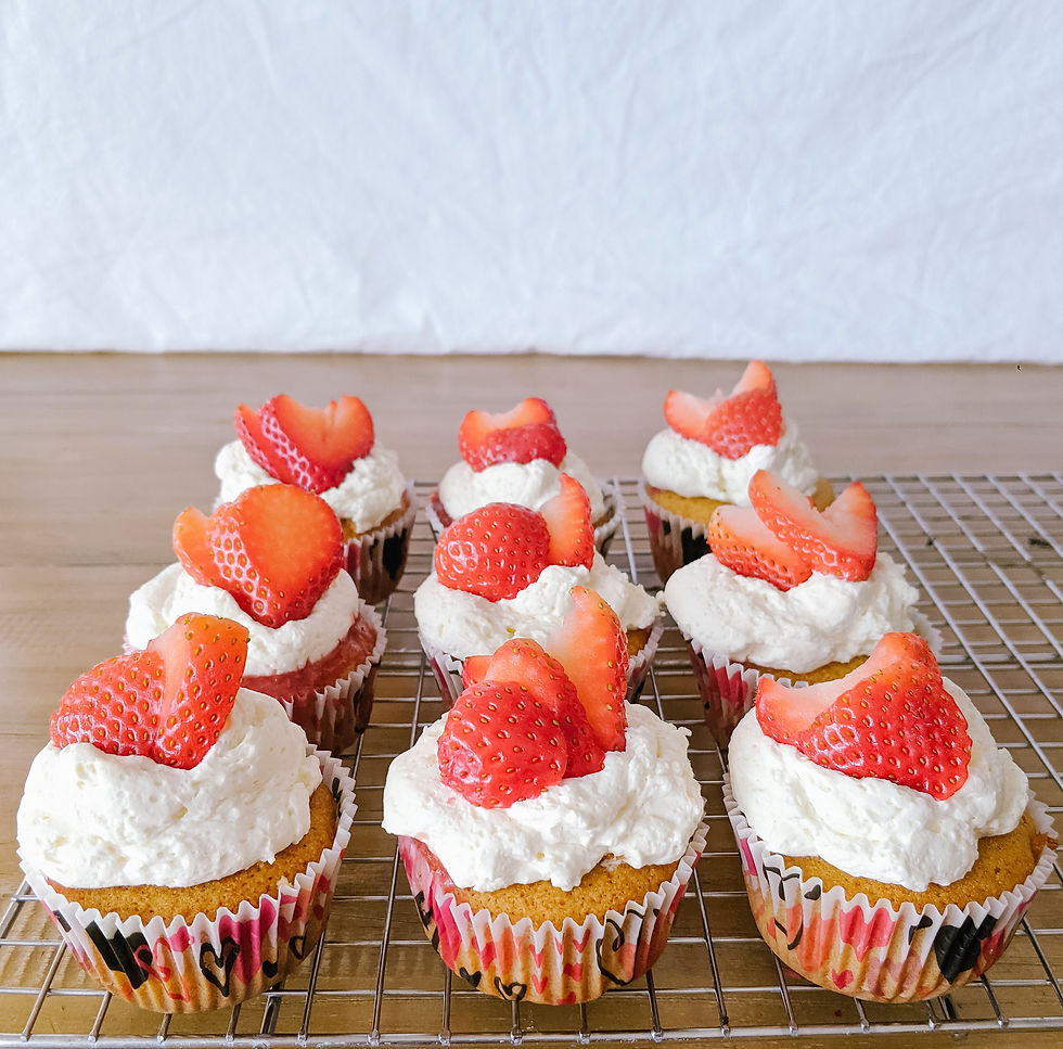 Rows of paleo strawberry shortcake cupcakes are shown with fluffy white whip cream topping, and bright red strawberries on top