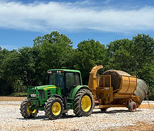 John Deere green tractor hauling a hay shredder that is used for erosion and drainage control