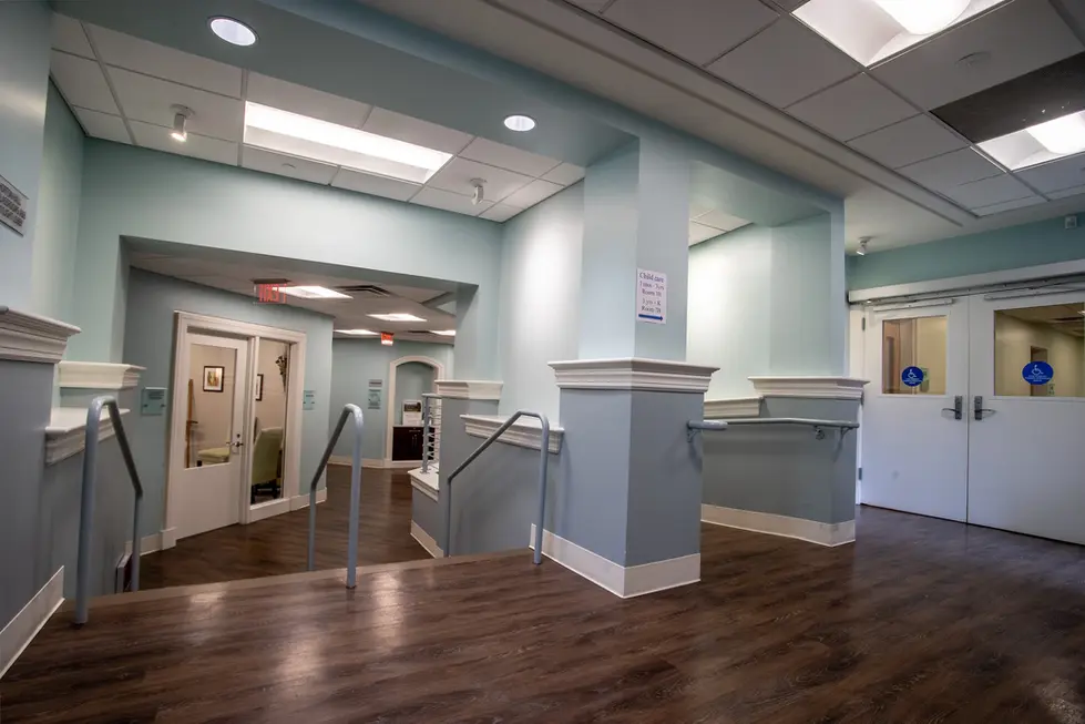 Interior view of a building's hallway and staircase with wooden floors and light paint.