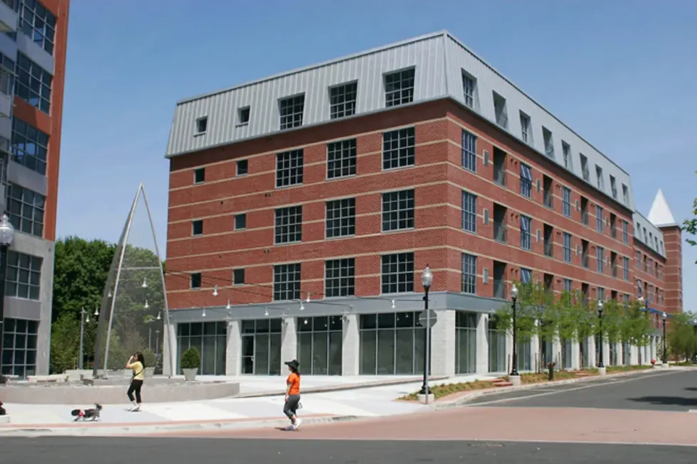 Brick building with many windows and people walking, clear sky background