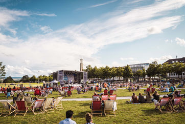 Open Air Festival bei sommerlichem Wetter mit Liegestühlen vor der Bühne, Eventfotografie