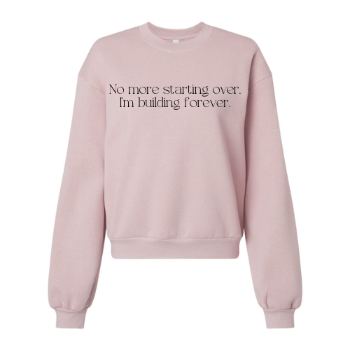 Thumbnail: Light pink crewneck sweatshirt with the phrase "No more starting over. I'm building forever." on the front.