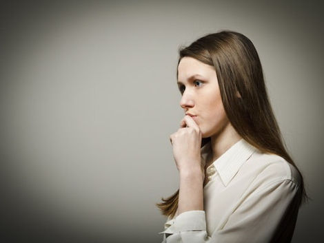 An anxious young woman biting her nails, symbolising self-doubt and overthinking before therapy for self-doubt and confidence building.