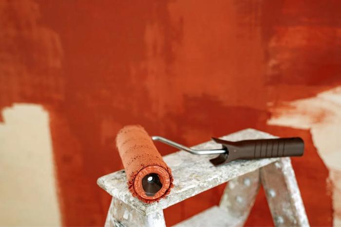 A paint roller placed on a wooden ladder
