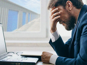 A business man frustrated in front of his laptop, self storage can be seen outside the window