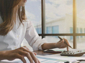 A woman doing calculations with self storage units visible outside the window behind her