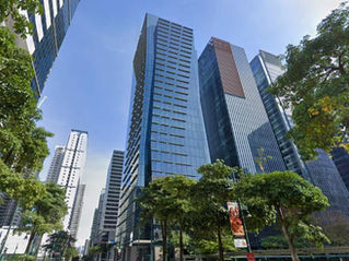 太陽の光が降り注ぐボニファシオ・グローバル・シティのスカイラインを、活気あふれるストリートレベルから捉えた景観。洗練されたガラス張りの高層ビルが、青々と茂る並木の上にそびえ立っています。