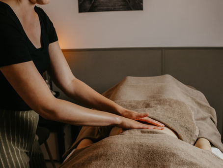 Nieuwe moeder ontvangt een ontspannende massage na de bevalling, gericht op herstel en rust in een warme praktijkruimte.
