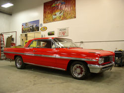 Side view of a finished red 1961 Pontiac Bonneville, with chrome trim.