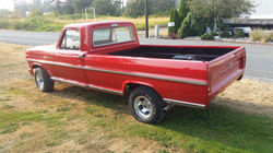 Side of red 1968 Ford F100 Truck with a chrome trim down middle