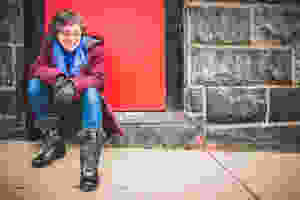 Sarah Blake by JPG Photography. Author of Mr. West, Let's Not Live on Earth and Naamah. Brick wall, red door, jeans, gloves and boots.