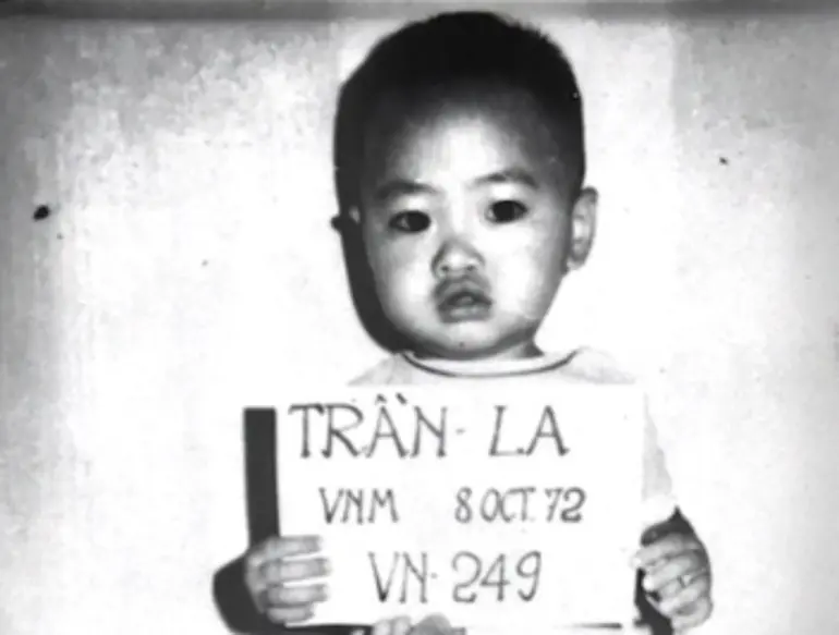 Saul Tran Cornwall as a toddler, holding a sign with his name and date of birth at the orphanage he was evacuated from in Vietnam in April 1975 [Courtesy of Saul Tran Cornwall]