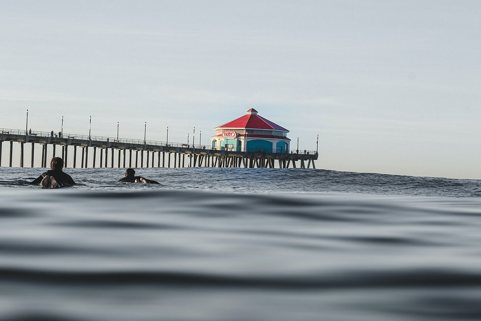 surfers in water with Huntington Beach pier in background