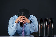 A person holding an alcohol bottle, indicating addiction to drinking