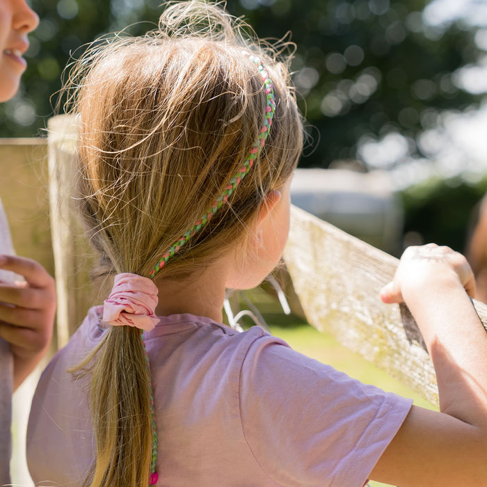 Zwei Mädchen beobachten ein Pferd hinter einem Zaun, umgeben von Natur. Ferienbauernhof Mau
