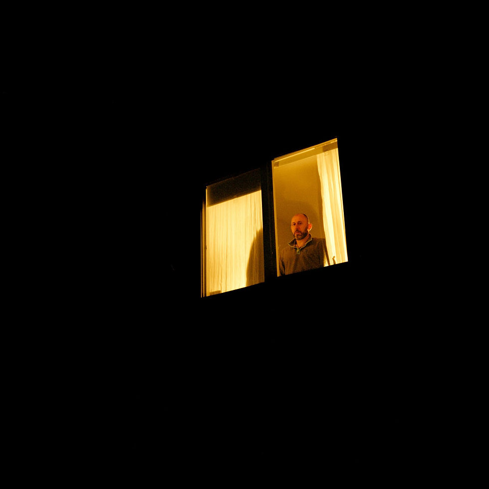 Person silhouetted in dimly lit window at night