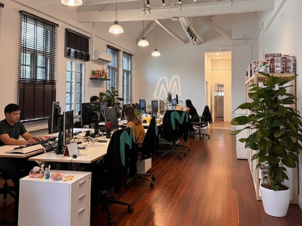 Open office space with desks, computers with an M sign on the wall.
