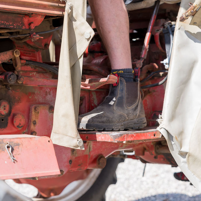 Person steigt auf einen roten Traktor, nah, Schuh, Bein, HOFLEBEN, Ferienbauernhof Mau.
