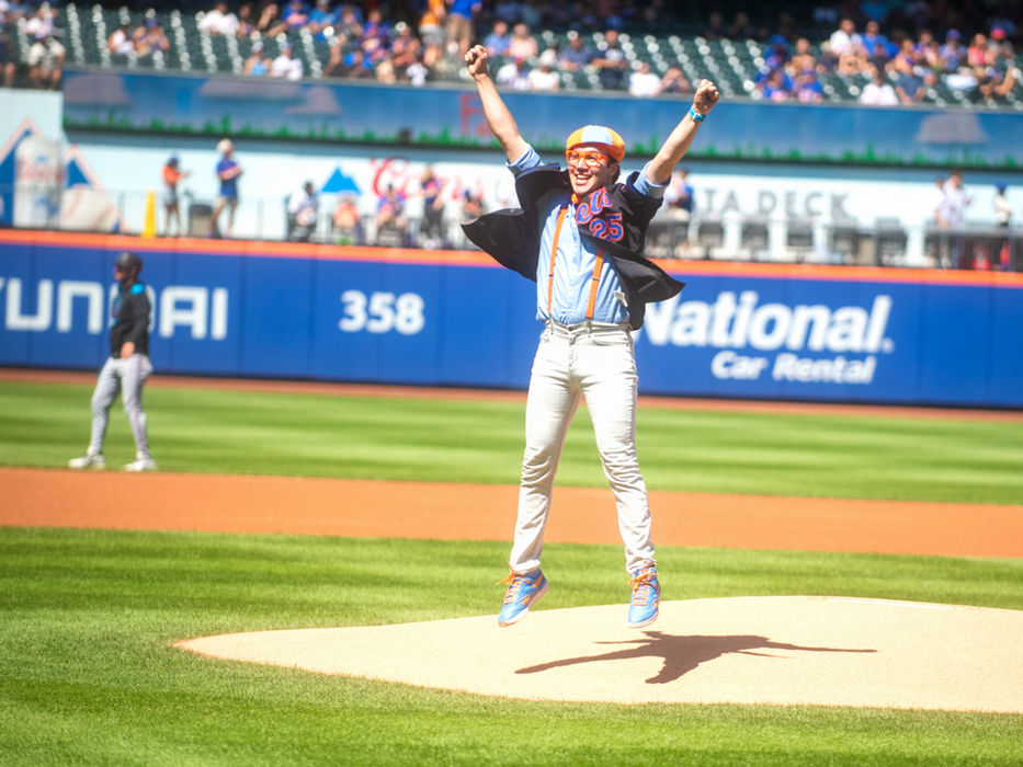 Blippi jumps in excitement at a baseball field