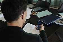 20.01-Widex-MOMENT-Office-Man-sitting-at-desk-seen-from-back-smartphone-in-hand (1)-min.jp