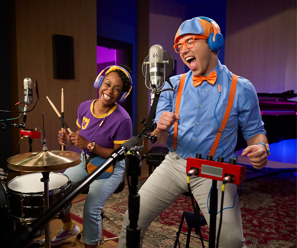 Blippi joyfully sings into the microphone while Meekah plays drums in the studio.