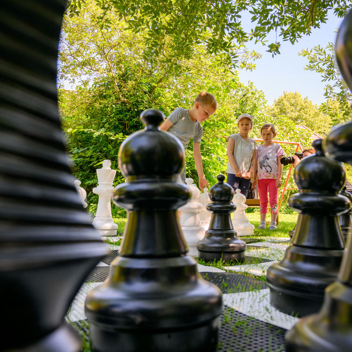 Kinder spielen Schach im Freien mit großen Figuren, Ferienbauernhof Mau.