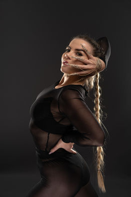Woman poses with a hand over her face, wearing black clothing, STUDIO PHOTOSHOOTS