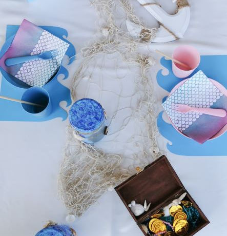 Wundervoll inszenierter Tisch für einen Kindergeburtstag, der mit den Dekoartikeln eines Meeres, wie einer Schatzkiste, Anker, Netze, Muscheln verschönert wurde.