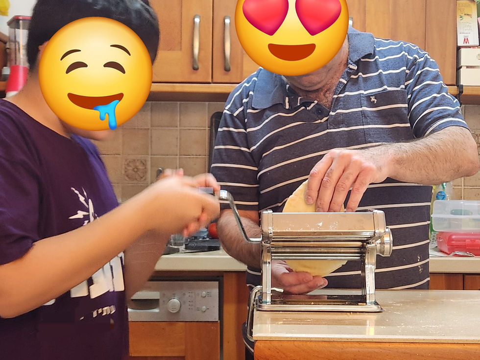 אב ובנו מכינים פסטה במכונת פסטה שמרדדת את הבצק. הפרצופים שלהם מוסתרים עם אימוג'יז. צילום גל אפרתי 
