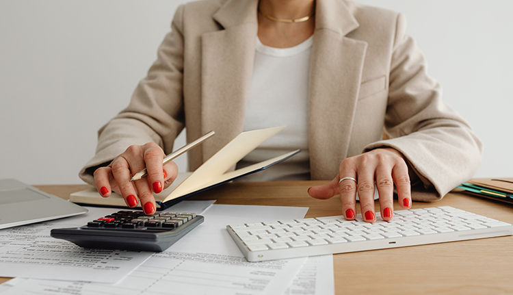 a woman with one hand on a calculator and one had on a keyboard